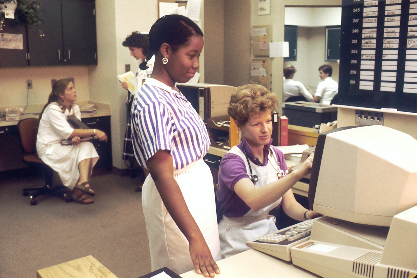 Two healthcare professionals working at computers in an office.