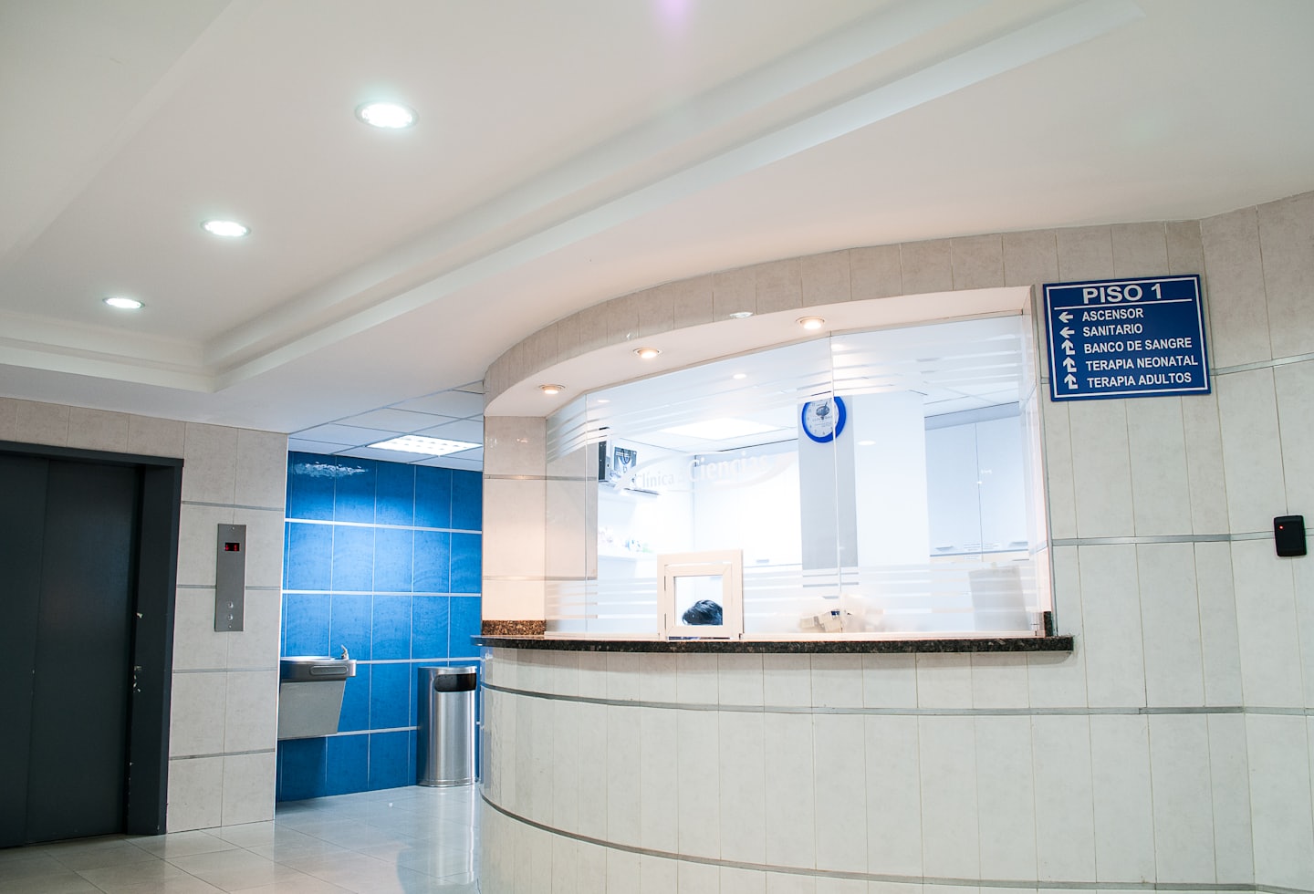 Modern reception area with curved desk and blue tiles.